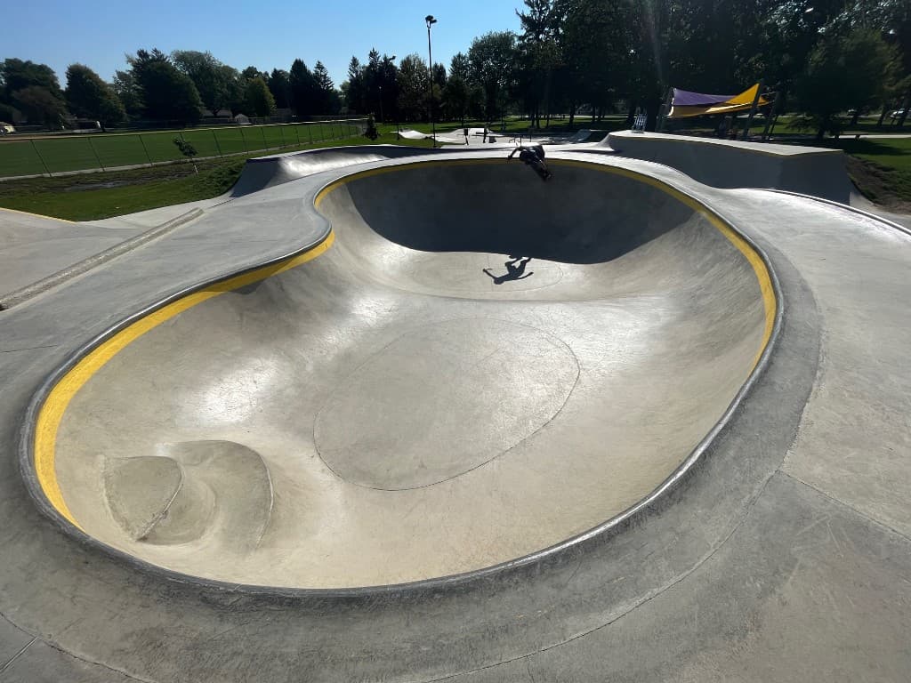 Skateboarder carving a concrete bowl at a community skatepark