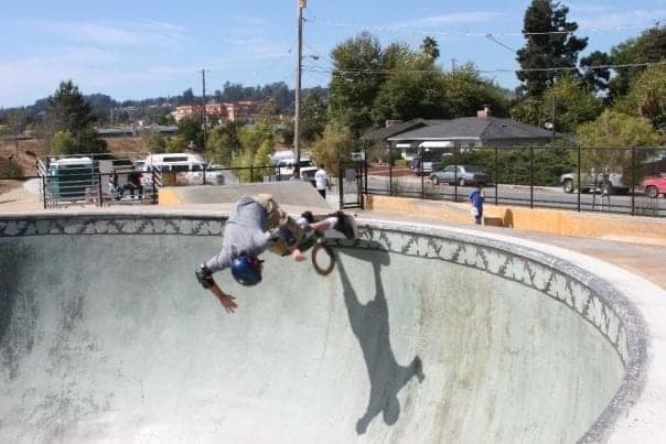 Skateboarder performing a handplant in a concrete bowl